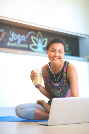Sporty smiling woman using laptop in bright roomの写真素材
