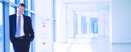 Portrait of businessman standing near window in officeの写真素材