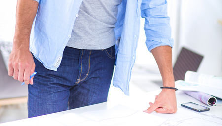 Portrait of male designer in hat with blueprints at deskの写真素材