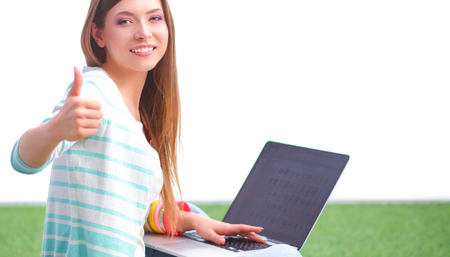 Young woman with laptop sitting on green grassの写真素材