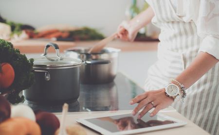 Young woman using a tablet computer to cook in her kitchenの写真素材