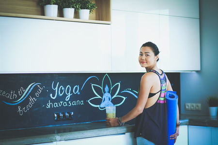 Portrait of smiling woman holding in her hand a yoga mat while standing at studio. Yoga. Woman. Wellnessの写真素材