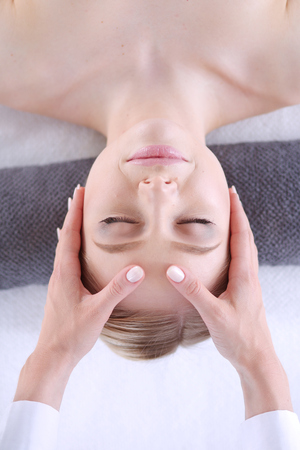 Young woman lying on a massage table,relaxing with eyes closed.の写真素材