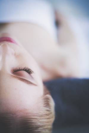 Young woman lying on a massage table,relaxing with eyes closed.の写真素材