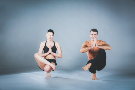 Young couple practicing acro yoga on mat in studio together. Acroyoga. Couple yoga. Partner yoga.の写真素材