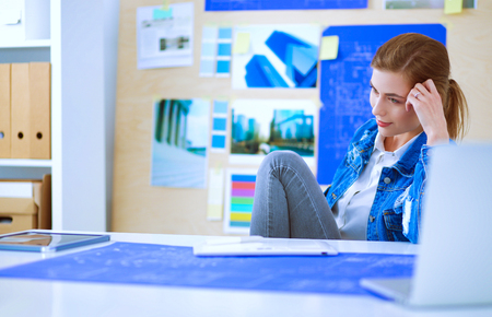 Two young woman standing near desk with instruments, plan and laptop.の写真素材