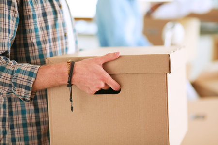 Young couple carrying big cardboard box at new home.Moving house