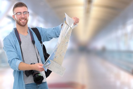 Handsome tourist looking at map standing on streetの写真素材