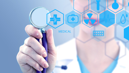 Woman doctor holding medical stethoscope and working with modern medical iconsの写真素材