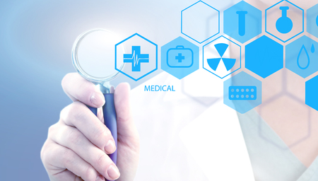 Woman doctor holding medical stethoscope and working with modern medical icons.の写真素材