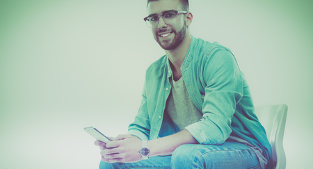 Young man sitting on chair and using mobile phoneの写真素材