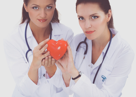 Two woman doctor holding a red heart, isolated on white backgroundの写真素材