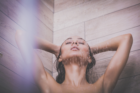 Young beautyful woman under shower in bathroom.の写真素材