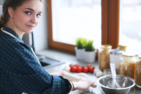 Beautiful woman cooking cake in kitchen standing near desk.の写真素材