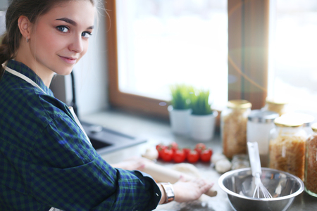 Beautiful woman cooking cake in kitchen standing near desk.の写真素材