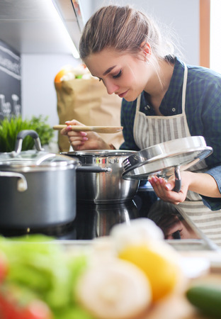 Young woman standing by the stove in the kitchen .の写真素材
