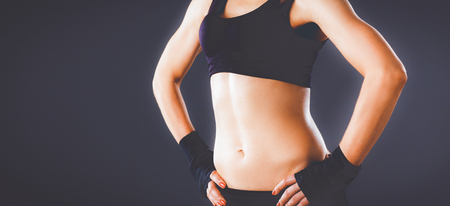 Muscular young woman  standing on gray backgroundの写真素材