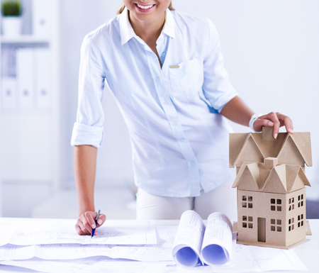 Portrait of female architect with blueprints at desk in office, isolatedの写真素材