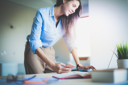 Beautiful young business woman sitting at office desk and talking on cell phone. Business womanの写真素材