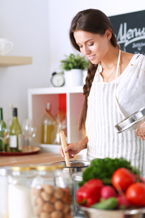 Cooking woman in kitchen with wooden spoonの写真素材