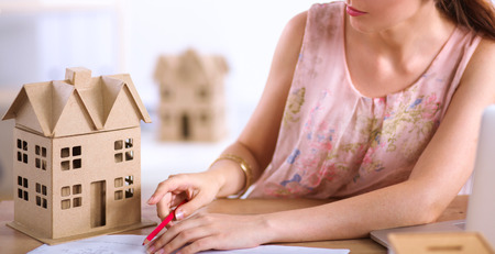 Portrait of female architect with blueprints at desk in officeの写真素材