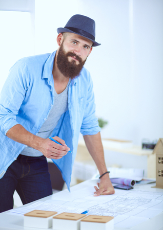 Portrait of male designer in hat with blueprints at deskの写真素材