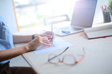 Young woman sitting at office table with laptop. Young woman. Laptopの写真素材