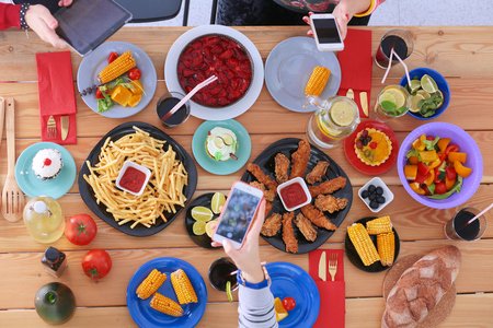 Top view of group of people having dinner together while sitting at wooden table. Food on the table. People eat fast food. Photograph foodの写真素材