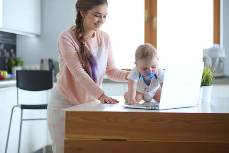 Mother with her baby in the bright kitchen at home.の写真素材