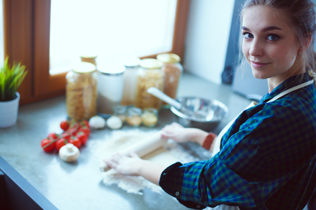 Beautiful woman cooking cake in kitchen standing near desk.の写真素材