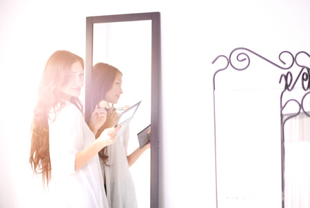 Young woman looking herself reflection in mirror at home. Young woman.の写真素材