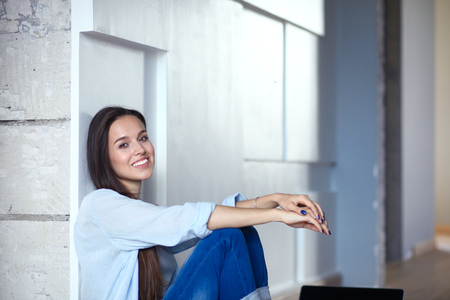 Young beautiful woman at home sitting on the floor with laptop. Young beautiful woman.の写真素材