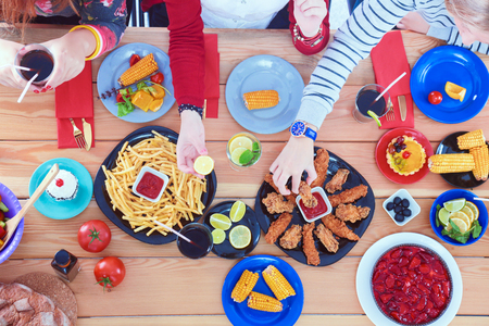 Top view of group of people having dinner together while sitting at wooden table. Food on the table. People eat fast foodの写真素材