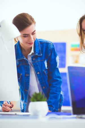Two young woman standing near desk with instruments, plan and laptop.の写真素材