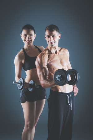 Athletic man and woman with a dumbells. Personal fitness instructor. Personal training.の写真素材