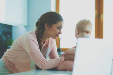 Mother with her baby in the bright kitchen at home.の写真素材