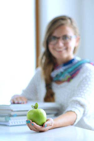 Female college students sitting on the desk with apple on a pile of books. Student. Collegeの写真素材