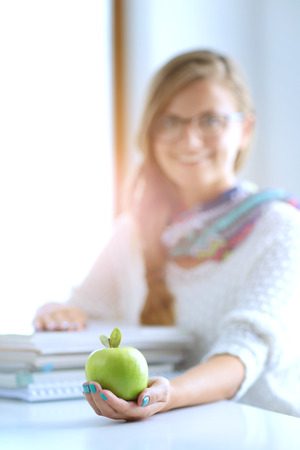 Female college students sitting on the desk with apple on a pile of books. Student. Collegeの写真素材