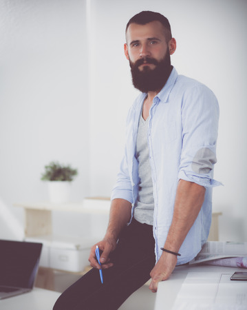 Portrait of male designer in hat with blueprints at deskの写真素材