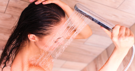 Young beautyful woman under shower in bathroomの写真素材