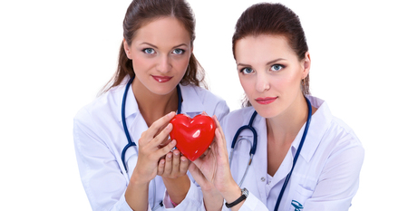 Two woman doctor holding a red heart, isolated on white backgroundの写真素材