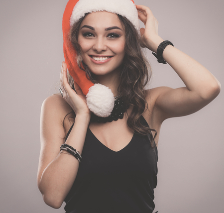 Attractive smiling woman in Santa Cap. Isolated over a gray background.の写真素材