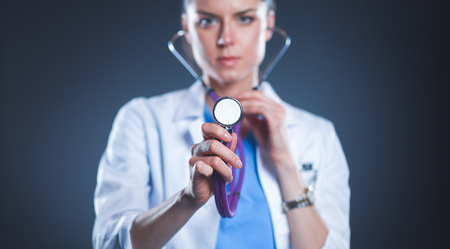 Female doctor with a stethoscope listening, isolated on grey backgroundの写真素材