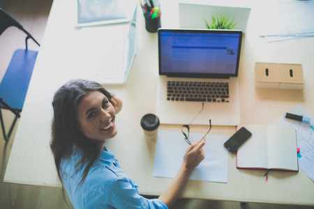 Young woman sitting in office table, looking at laptop computer screen . Young womanの写真素材