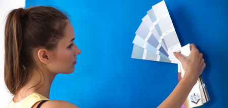 Young beautiful woman holding color palette , standing near wall.の写真素材