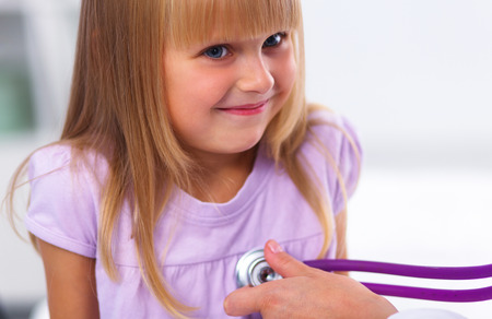 Female doctor examining child with stethoscope at surgeryの写真素材