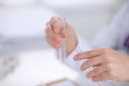 Woman researcher is surrounded by medical vials and flasks, isolated on white.の写真素材