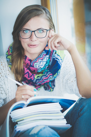 Young woman sitting at a desk among books. Studentの写真素材