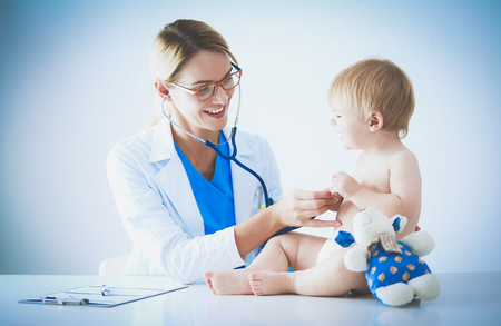 Female doctor is listening kid with a stethoscope in clinicの写真素材