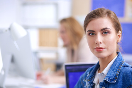 Two young woman sitting near desk with instruments, plan and laptop.の写真素材